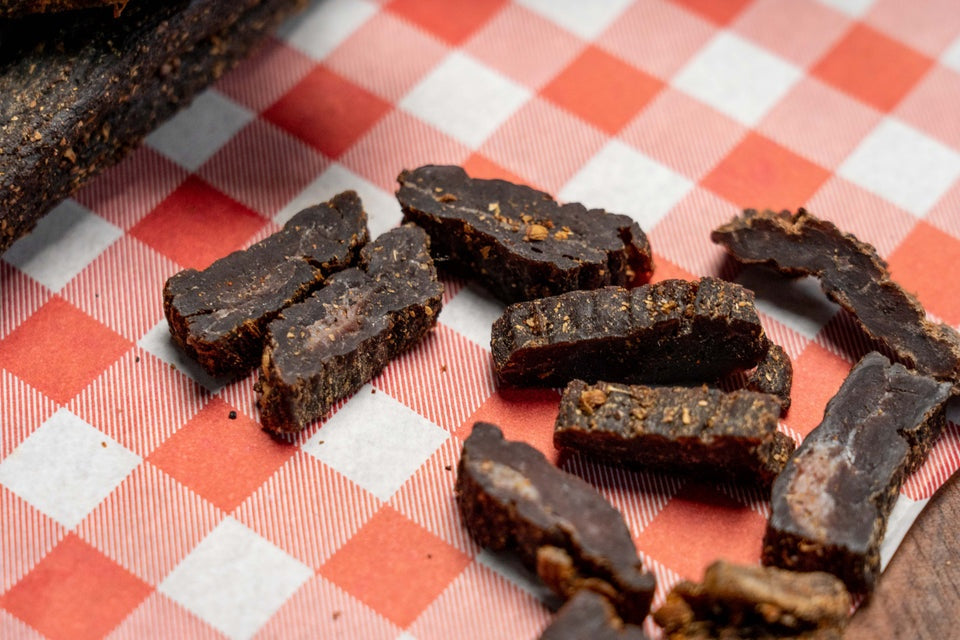 Traditional beef biltong cut into bite-sized pieces and served on checkered paper by Aussie Biltong.